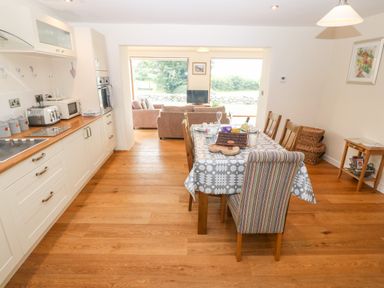 A kitchen and dining area with wooden cabinets and table at Llofft Yr Yd in Llandwrog near Dinas Dinlle