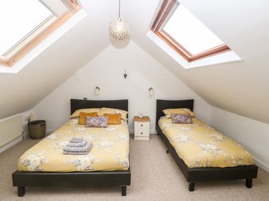 A bedroom with two beds under slanted ceilings with skylight windows at Llofft Yr Yd in Llandwrog near Dinas Dinlle
