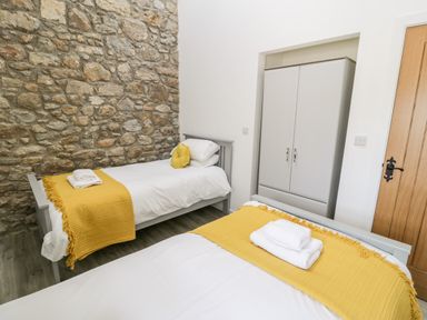 A bedroom with two single beds with yellow throws towels and a wardrobe at 1 Mountain View Talwrn near Llangefni