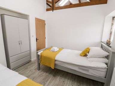 A bedroom with two single beds a wardrobe and wooden ceiling beams at 1 Mountain View in Talwrn near Llangefni