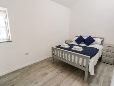 A bedroom with a bed with blue pillows and a blanket and two nightstands at 1 Mountain View Talwrn near Llangefni