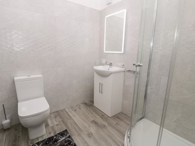 A bathroom with a toilet sink with cabinet mirror and a glass shower enclosure at 1 Mountain View in Talwrn near Llangefni