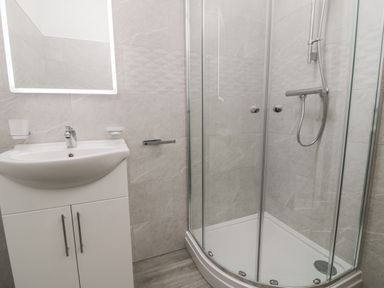 A bathroom with a sink and a glass enclosed shower at 1 Mountain View in Talwrn near Llangefni