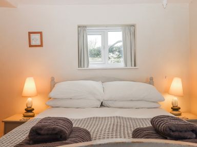 A bedroom with a bed and lamps at Yew Tree Cottage in Stoke Fleming