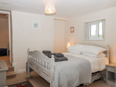 A bedroom with a bed and nightstand at Yew Tree Cottage in Stoke Fleming