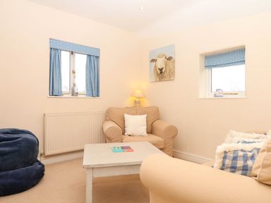 A living room with an armchair and a table at Yew Tree Cottage in Stoke Fleming