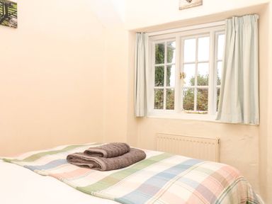 A bedroom with a bed and window at Yew Tree Cottage Stoke Fleming