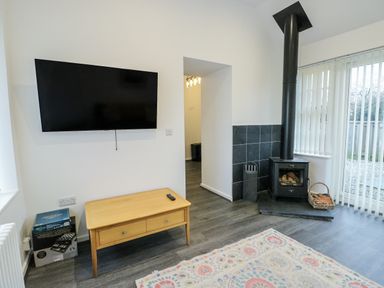 A living room with a television and a wood stove at 2 Mountain View Talwrn near Llangefni
