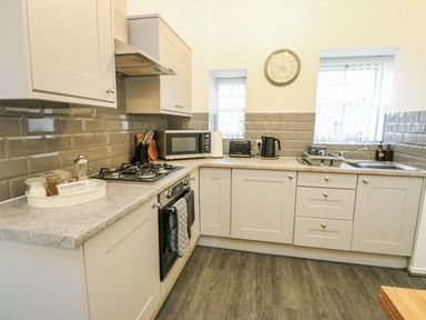 A kitchen with a gas stove and microwave at 2 Mountain View Talwrn near Llangefni