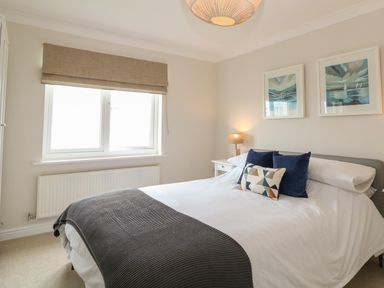 A bedroom with a bed side table lamp and two paintings above the bed at Breakers in Newquay