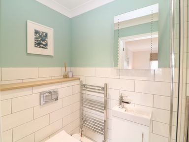A bathroom with a sink a mirror a towel radiator and a framed picture on the wall at Breakers in Newquay