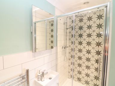 A bathroom with a shower enclosure and a sink with a mirror above at Breakers in Newquay