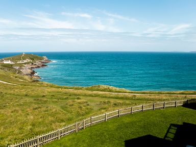A coastal landscape with a fence grassy fields and sea at Breakers in Newquay