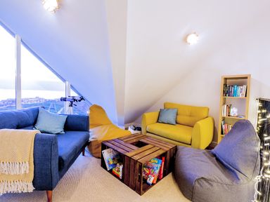 A sitting area with blue and yellow sofas a bean bag wooden crate coffee table and a bookshelf at Breakers in Newquay