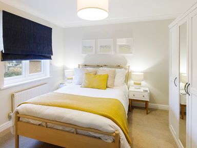 A bedroom with a wooden bed and yellow throw at Breakers in Newquay