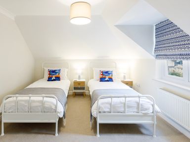 A bedroom with two single beds a window and nightstands at Breakers in Newquay