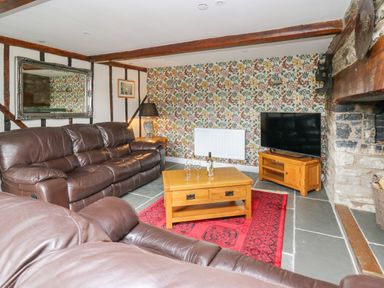 A living room with brown leather sofas wooden coffee table and television on wooden stand at Cwmfadog Llanafan-fawr near Beulah