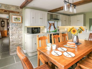 A kitchen with wooden dining table and chairs plates cups cake and sunflowers Cwmfadog Llanafan-fawr near Beulah