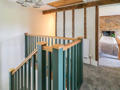 A stairway with green and wooden railings next to a bedroom with stone wall and bed at Cwmfadog in Llanafan-fawr near Beulah