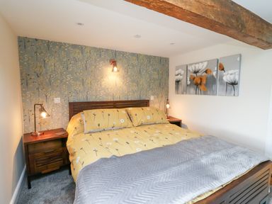 A bedroom with a double bed yellow bedding and bedside tables with lamps at Cwmfadog Llanafan-fawr near Beulah