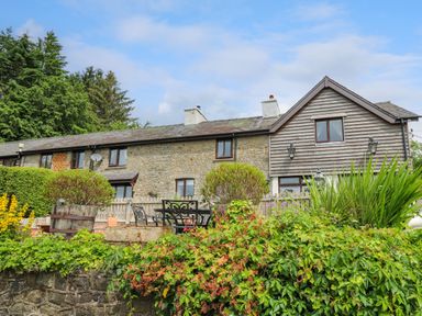 A stone and wood exterior house with garden and outdoor seating at Cwmfadog Llanafan-fawr near Beulah