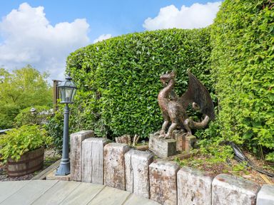 A garden area with a metal dragon sculpture wooden posts and a lamp post at Cwmfadog in Llanafan-fawr near Beulah