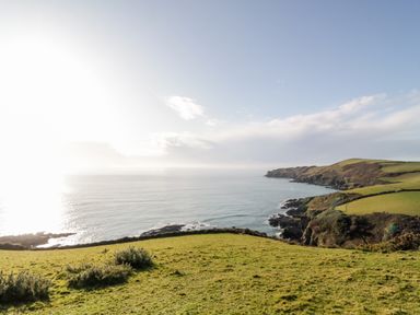 A coastal landscape with grassy cliffs beside the sea at 2 Rose Cottages Lansallos near Polperro