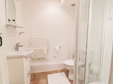 A bathroom with a sink cabinet mirror towel rail toilet and shower enclosure at 3 Rose Cottages Lansallos near Polperro