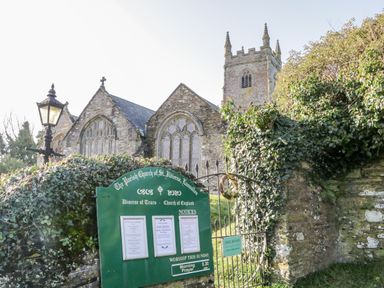 A stone church building with gothic windows behind a gate and notice board at 4 Rose Cottages Lansallos near Polperro
