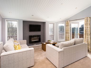 A living room with two sofas a wall mounted TV and a fireplace at Waternook Lodge in South Lakeland Leisure Village