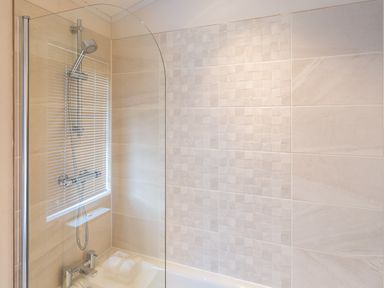 A bathroom shower area with a glass screen and tiled walls at Waternook Lodge in South Lakeland Leisure Village