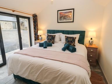 A bedroom with a double bed two bedside tables with lamps and sliding glass doors at The Cwtch in St Brides Major