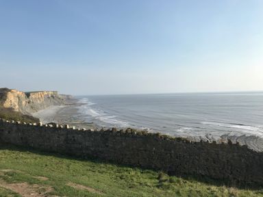 A coastal view with cliffs a stone wall and the sea at The Cwtch in St Brides Major