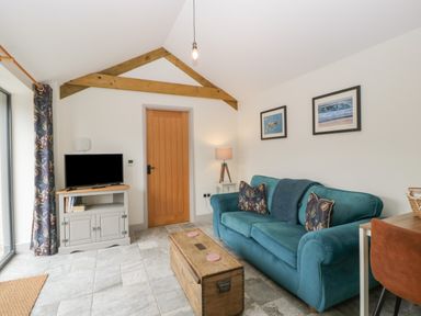 A living room with a blue sofa and wooden chest coffee table at The Cwtch in St Brides Major