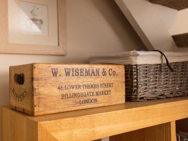 A wooden box with text next to a wicker basket on a wooden shelf at Old Post Office in Bull Bay