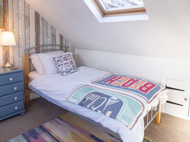 A bedroom with a single bed a blue chest of drawers a lamp and a skylight at Old Post Office Bull Bay