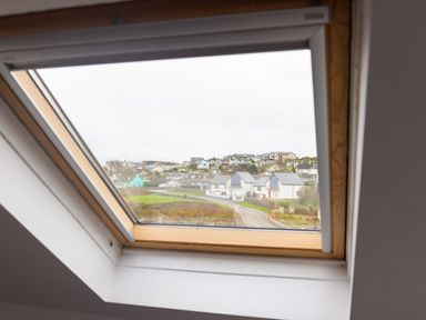 A view of houses and a road through a roof window at Old Post Office in Bull Bay