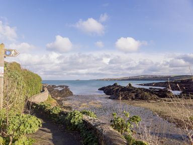 A coastal path with a walking sign beside the sea and rocky shoreline at Old Post Office in Bull Bay