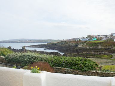 A coastal view with rocky shoreline bushes and houses on cliffs at Old Post Office in Bull Bay