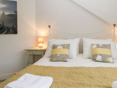 A bedroom with a double bed pillows bedside table with a lamp and a painting on the wall at Sethera in Ambleside