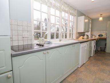 A kitchen with white cabinets a sink stovetop and appliances by a window at Sethera in Ambleside