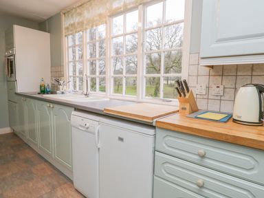 A kitchen with a countertop sink dishwasher knife block and kettle near large windows at Sethera in Ambleside