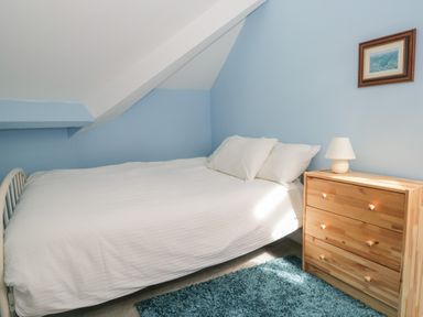 A bedroom with a double bed next to a wooden dresser with a lamp and a small framed picture on the wall at Sethera in Ambleside