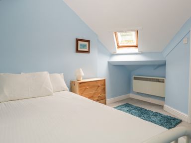 A bedroom with bed dresser lamp rug and skylight window at Sethera in Ambleside