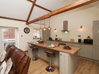 A kitchen with an island and bar stools at Crabtree Cottage in Suffield near Scalby
