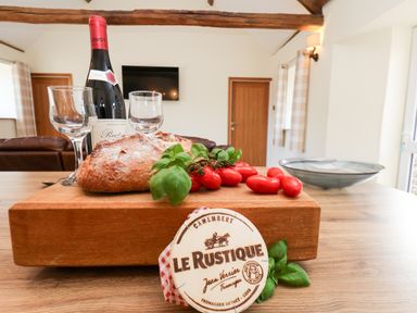 A kitchen with a cutting board, wine, cheese, and vegetables at Crabtree Cottage, Suffield near Scalby