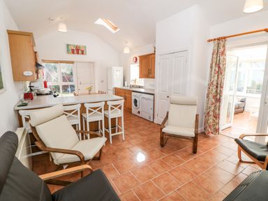 A kitchen and sitting area with chairs a countertop and appliances at Y Buarth in Waunfawr