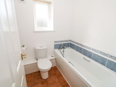 A bathroom with a toilet and a bathtub with blue tiled walls at Y Buarth in Waunfawr