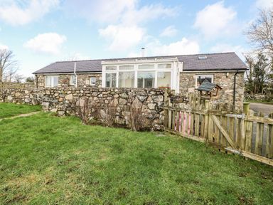A stone cottage with a small garden and wooden gate at Y Buarth in Waunfawr