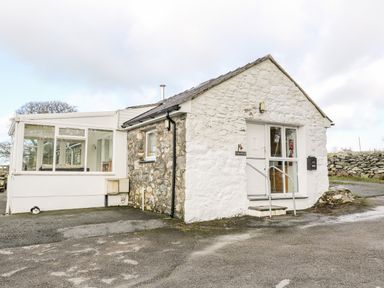 A stone and white painted cottage with a small porch and a mailbox outside at Y Buarth in Waunfawr